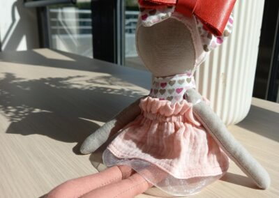 Poupée câline Dena, noeud rouge et robe rose poudré – Noundoll